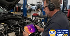 Technician using advanced AI-powered tools in Gregg Smith Automotive to detect a micro-leak inside a car’s air conditioning system using a thermal tablet.
