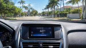 A digital thermometer in a car's air conditioning vent displays a crisp 40°F, with a blurry, sun-drenched Florida street visible through the windshield, demonstrating professional AC performance verification.